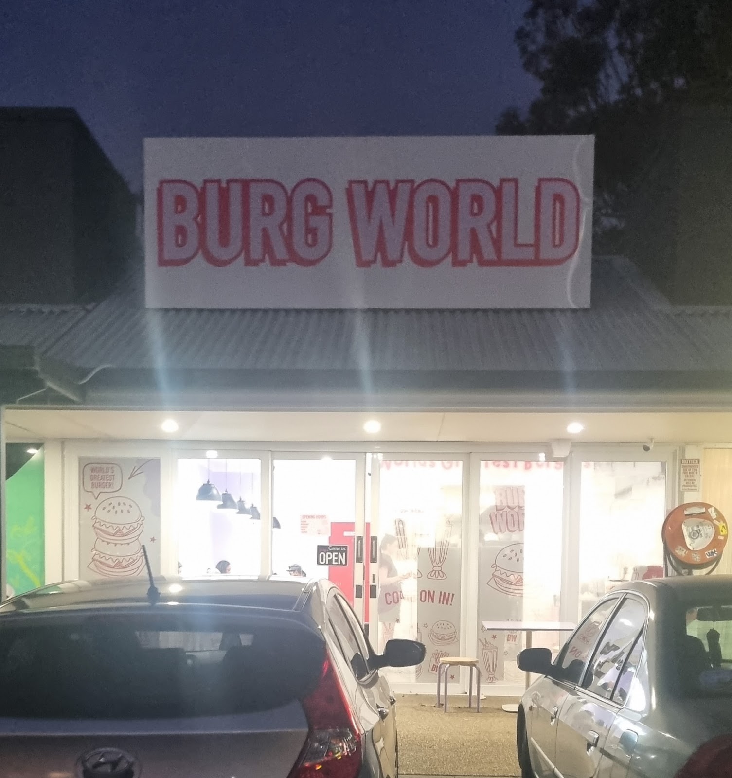 The Burg World shopfront at dusk with its lit sign, 20 Siganto Drive, Helensvale
