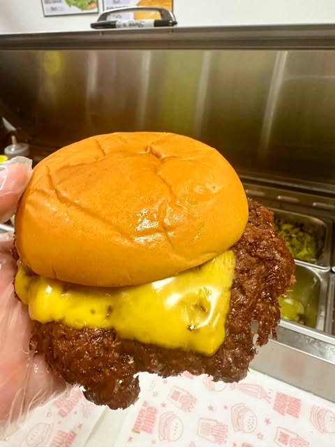 A crumbed chicken burger held up in the Burg World kitchen